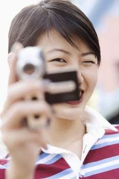 Portrait of a young woman holding a digital camera