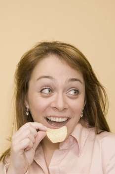 Close-up of a mid adult woman eating a potato chip and smiling