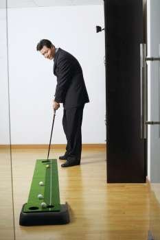 Side profile of a businessman practicing golf in a club