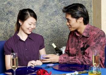 Young man giving a gift to a young woman in a restaurant