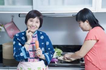 Portrait of a senior woman and her daughter preparing food in a kitchen