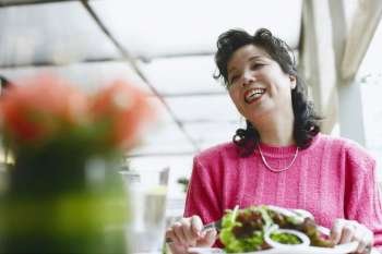 Low angle view of a mature woman seated at the table in a restaurant smiling