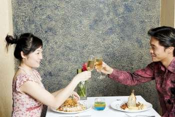 Side profile of a young couple toasting with champagne in a restaurant