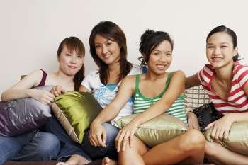 Portrait of four young women sitting on a couch and smiling