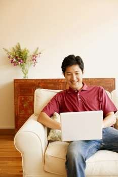 Young man sitting on a couch and using a laptop