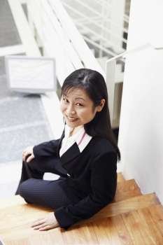 High angle view of a businesswoman sitting on the staircase and smiling
