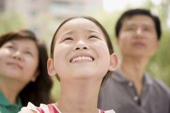 Close-up of a girl smiling with her parents in the background