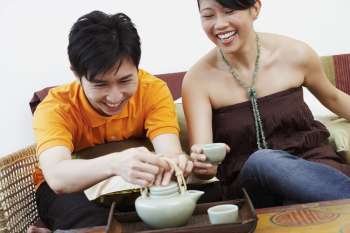 Close-up of a young couple with a kettle and coffee cups