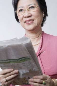 Close-up of a senior woman holding a newspaper