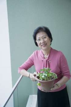 Portrait of a senior woman holding a potted plant and smiling