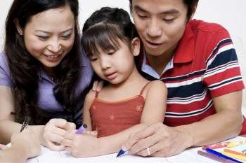 Close-up of parents drawing on paper with their daughter