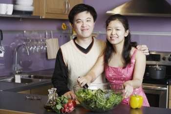 Portrait of a young man standing with a mid adult woman in the kitchen