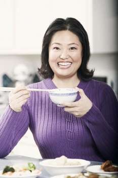 Portrait of a mature woman holding a bowl with a pair of chopsticks