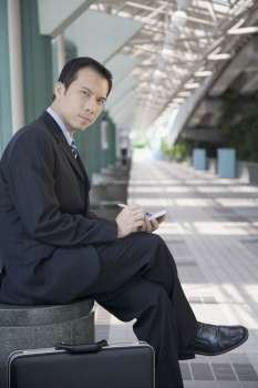 Portrait of a businessman sitting and using a palmtop