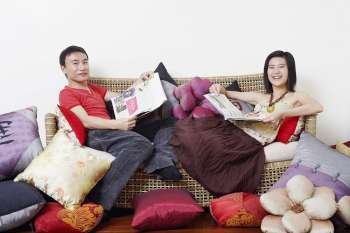 Portrait of a mid adult man and a young woman reclining on a couch and smiling