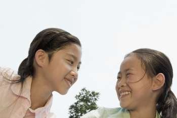 Close-up of a girl smiling with her sister and looking at each other