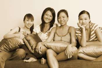 Portrait of four young women sitting on a couch and smiling