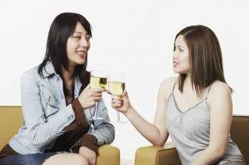 Close-up of two young women toasting with wineglasses