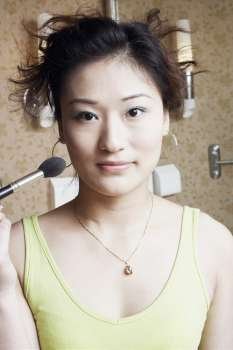 Portrait of a young woman applying make-up on her face
