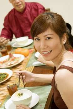 Portrait of a young woman eating with chopsticks