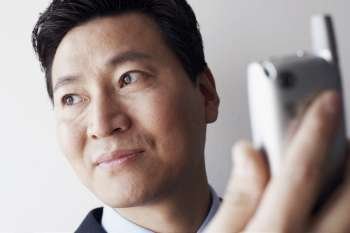 Close-up of a businessman holding a mobile phone thinking