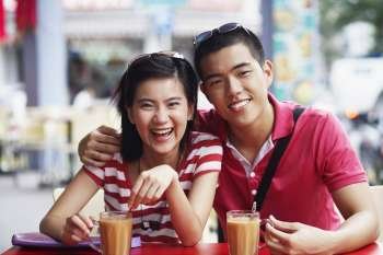 Portrait of a young couple sitting at a sidewalk cafe and smiling