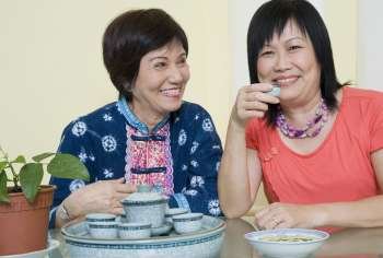 Portrait of a mature woman holding a tea cup and smiling with a senior woman sitting beside her