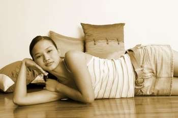 Portrait of a young woman lying on the floor with cushions behind her