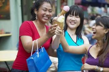 Close-up of three young women holding ice-cream cones
