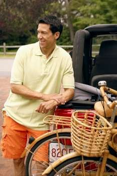Mature man leaning against a sports utility vehicle