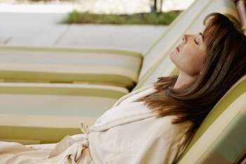 Side profile of a mid adult woman reclining on a lounge chair