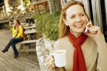 Mature woman talking on a mobile phone and holding a cup of tea