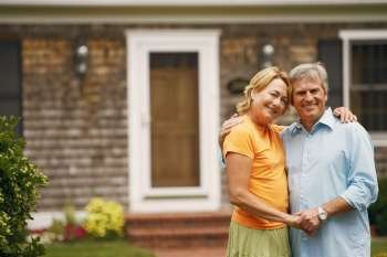 Portrait of a mature couple standing with their arms around each other in front of a house