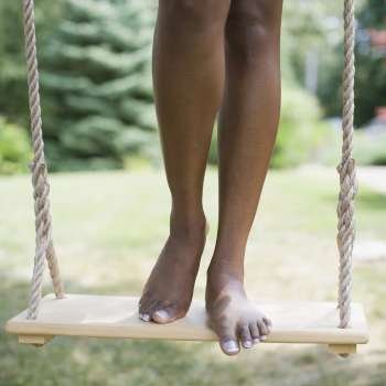 Low section view of a mid adult woman standing on a rope swing