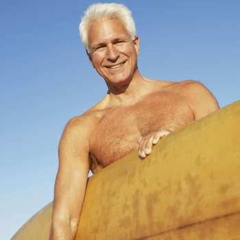 Portrait of a mature man holding a surfboard under his arm