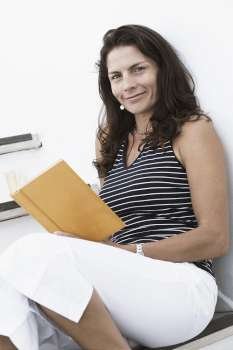 Portrait of a mid adult woman holding a book and smirking