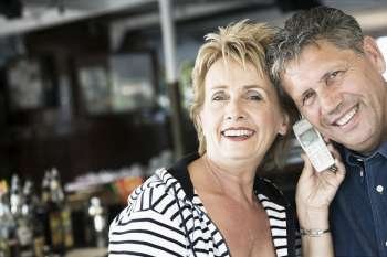 Portrait of a mature woman and a senior man listening to a mobile phone and smiling