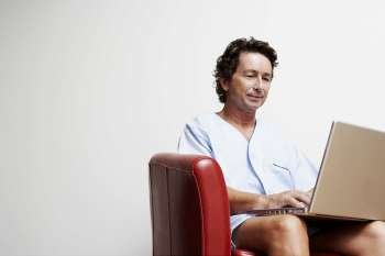Mature man sitting in an armchair and using a laptop