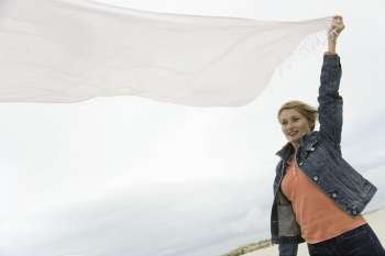 Low angle view of a mature woman holding up a shawl in wind