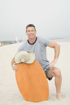 Portrait of a mature man holding a surfboard on the beach