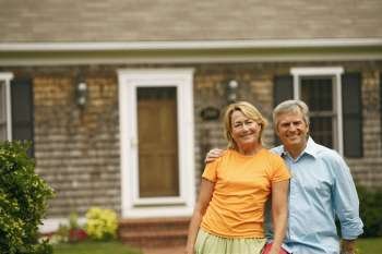 Portrait of a mature couple standing in front of a house