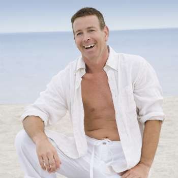 Portrait of a mature man kneeling on the beach and laughing
