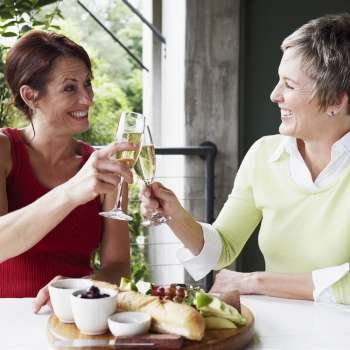 Close-up of two mature women toasting with champagne flutes