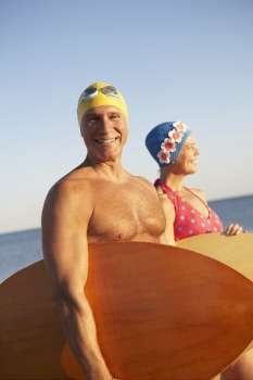 Portrait of a mature man with a mature woman holding surfboards on the beach