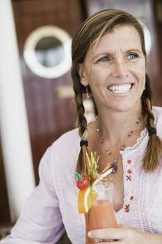Mid adult woman holding a glass of cocktail and smiling