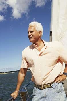 Mature man standing in a sailboat and smiling