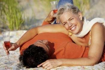 Portrait of a mature woman lying on the beach with a mature man