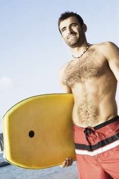 Low angle view of a mid adult man holding a surfboard