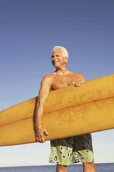 Mature man holding a surfboard under his arm