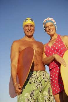 Portrait of a mature couple holding surfboards and smiling